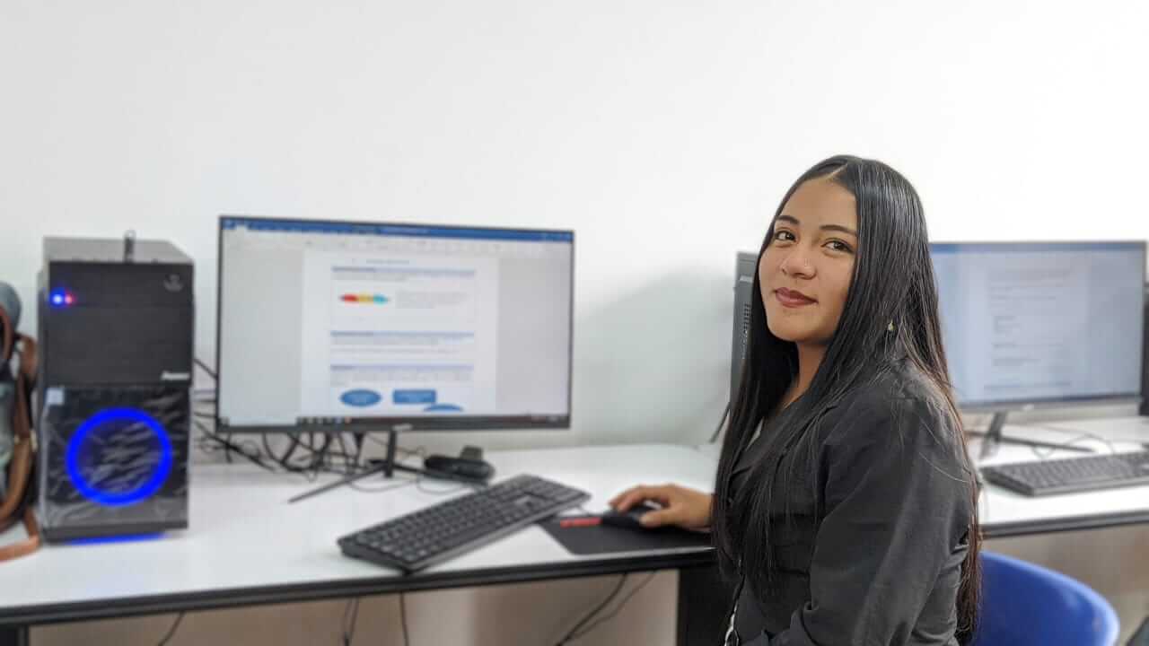 A young person sitting in front of a computer. Our social business model is based on creating shared value and measuring our success with impact indicators.