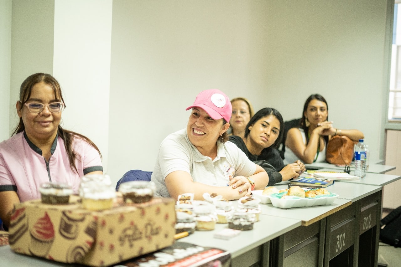 Un grupo de mujeres entablando conversación en una mesa Nuestro compromiso con el alto impacto se refleja en cada proyecto que emprendemos, buscando siempre mejorar la calidad de vida de las personas.