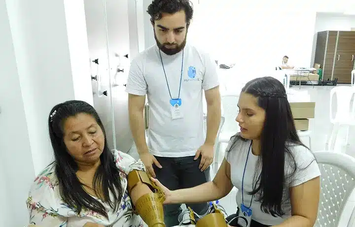 Three people, one of them showing their arm, ensuring their benefit from One Social Investment's social innovation.
