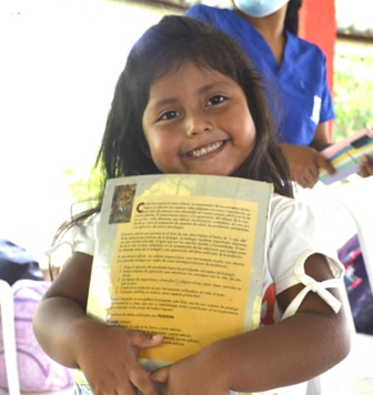 Niña sonriendo con un libro en sus brazos,