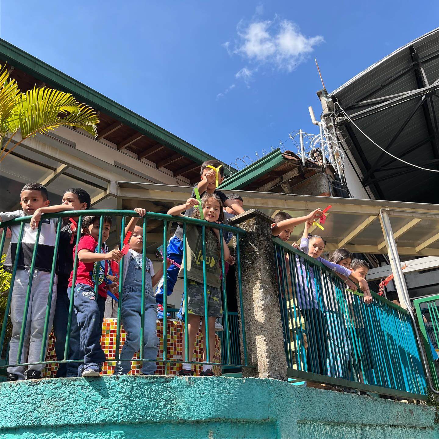 Niños y niñas en un barandal mostrando sus tareas realizadas , creando aprendizaje para el desarrollo sostenible que genera one inversión social