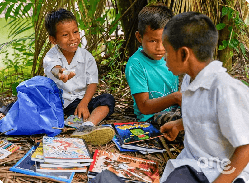 Three children (beneficiaries) sitting outdoors, observing what people supporting ONE Investment have donated