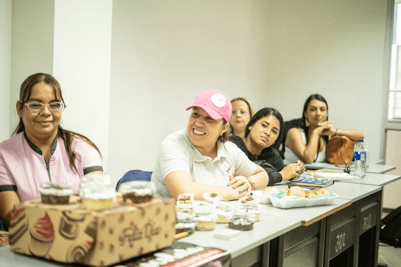Entrepreneurs sitting at a table, each showcasing businesses achieved thanks to ONE Investment.