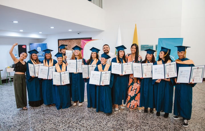 Grupo de graduados posa para una foto después de una ceremonia de graduación. Están vestidos con togas y birretes azules, sosteniendo diplomas en sus manos. Todos lucen sonrientes y felices, reflejando un sentimiento de logro y éxito en esta etapa de sus vidas. Esta imagen también simboliza el impacto positivo de la inversión social en la educación, resaltando cómo las oportunidades brindadas contribuyen al desarrollo personal y profesional de los graduados.