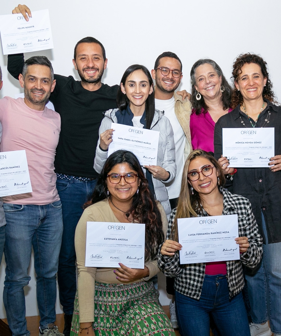 La imagen muestra a un grupo de personas sosteniendo certificados de finalización del programa